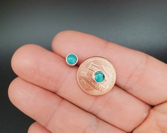May include: A pair of turquoise gemstone earrings, shown next to a US penny for size comparison.