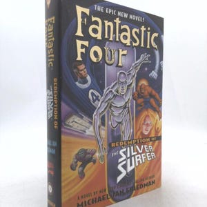 May include: A hardcover book titled "Fantastic Four: Redemption of the Silver Surfer." The cover features illustrations of the Silver Surfer, the Human Torch, and other characters. The book is a novel by Michael Jan Friedman.