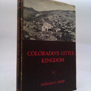 May include: A vintage book titled "Colorado's Little Kingdom" by Donald C. Kemp. The cover features a black and white photograph of a town nestled in a mountainous landscape. The title is in red letters.