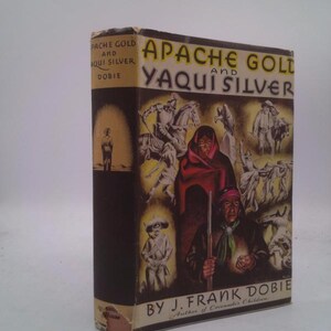 May include: A vintage book titled "Apache Gold and Yaqui Silver" by J. Frank Dobie. The cover features illustrations of Native Americans and cowboys, with text in yellow and black. The book's spine is dark brown.