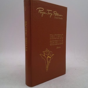 May include: A brown hardcover book titled "Pacific Shells" by Morris, part of the Roger Tory Peterson Field Guides series. The cover features gold lettering and a seashell illustration.