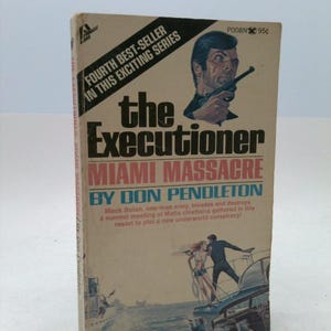 May include: Vintage paperback book titled "The Executioner: Miami Massacre" by Don Pendleton. The cover features a man holding a gun, a couple on a boat, and text that reads "Fourth Best-Seller in this Exciting Series."