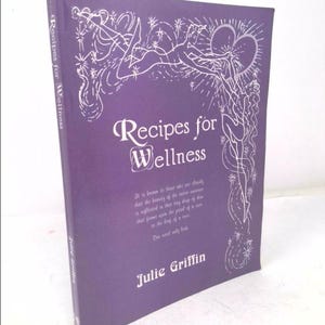 May include: A purple book titled "Recipes for Wellness" by Julie Griffin. The cover features a white illustration of two figures with a heart shape above them.
