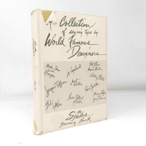 May include: A vintage book titled "A Collection of Sewing Tips by World Famous Designers." The cover is off-white with handwritten text and signatures. The book is a sewing guide.