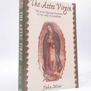 May include: A hardcover book titled "The Aztec Virgin" with an illustration of Our Lady of Guadalupe. The book's cover is cream-colored with the title in a stylized font. The spine is green with red rose accents.