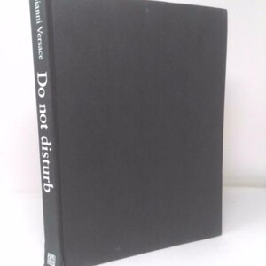 May include: A black hardcover book with the title "Do not disturb" and the author's name "Gianni Versace" printed in white on the spine.
