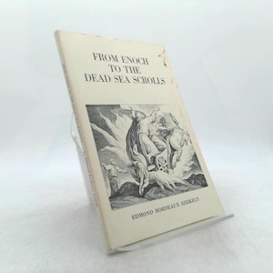 May include: A vintage book titled "From Enoch to the Dead Sea Scrolls" by Edmond Bordeaux Szekely. The book has a cream-colored cover with black text and a black and white illustration. The book is displayed on a clear stand.