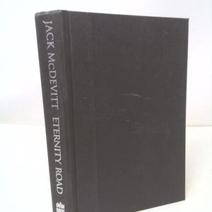 May include: A hardcover book titled "Eternity Road" by Jack McDevitt. The book has a dark cover with the title and author's name printed vertically in white. The Harper Prism logo is at the bottom.