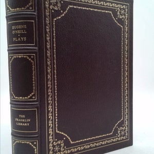 May include: A hardcover book with a dark brown leather cover and gold-colored decorative accents. The spine reads "EUGENE O'NEILL PLAYS" and "THE FRANKLIN LIBRARY". The cover features an ornate gold border.