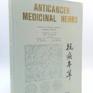 May include: A vintage book titled "ANTICANCER MEDICINAL HERBS" with gold lettering on a light green cover. The book includes Chinese text and illustrations. The author's name is Chang Minyi.