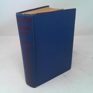 May include: A hardcover book with a blue cover and a spine featuring red text and decorative elements. The book's pages have a golden hue, suggesting age. The title is visible on the spine.