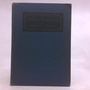 May include: A blue hardcover book with a dark rectangular label on the front cover. The label features the text Worship and Conduct Series for Beginners and Primaries in a decorative border. The book has a solid blue cloth-like texture.