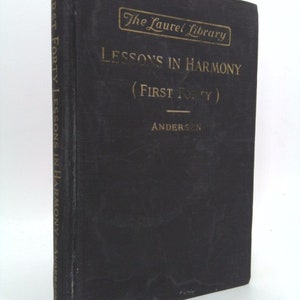 May include: A black book with gold lettering titled "Lessons in Harmony (First Forty)" by Andersen. The book is part of "The Laurel Library" series.