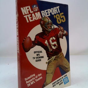 May include: A red, white, and blue book cover with the title "NFL Team Report '85". The cover features a football player wearing a red and gold uniform with the number 16 on his jersey. The book is an official NFL TV viewing guide with scouting reports of the 28 NFL teams.