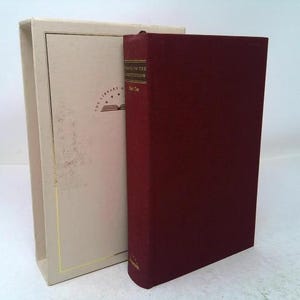 May include: A deep red hardcover book titled "Rights of the Constitution" standing next to its matching cream-colored slipcase. The slipcase features a gold-stamped logo with stars and an open book icon, while the book spine displays gold text.