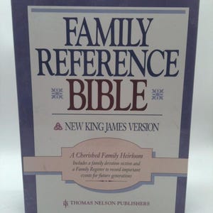May include: A hardcover book titled "FAMILY REFERENCE BIBLE" with "NEW KING JAMES VERSION" text. The cover is framed in a dark blue border with a light blue and white background. The text "A Cherished Family Heirloom" is also visible.