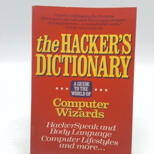 May include: A red book titled "the HACKER'S DICTIONARY" with yellow lettering. The book's subtitle reads "A Guide to the World of Computer Wizards." The cover includes quotes from Time Magazine.