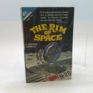 May include: Vintage paperback book titled "The Rim of Space" by A. Bertram Chandler. The cover features an astronaut, a circular hatch, and the title in yellow. The book is an Ace Double, with the numbers F-133 and 401 visible.