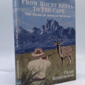 May include: A hardcover book titled "From Mount Kenya to the Cape: Ten Years of African Hunting" by Craig Boddington. The cover features a landscape with a hunter aiming a rifle at a kudu, with mountains in the background.