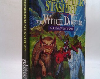 May include: Book cover for "The Witch Doctor" by Christopher Stasheff. The cover features a fantasy illustration of a monstrous creature, a knight on horseback, and an angel.