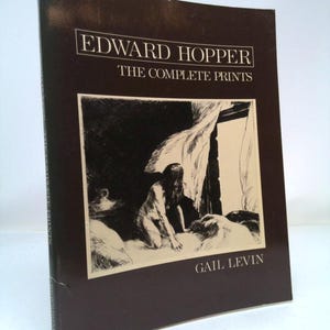 May include: A brown book with the title "Edward Hopper: The Complete Prints" and the author's name "Gail Levin" printed on the cover. The cover features a black and white illustration of a woman in a room.
