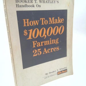 May include: A vintage book titled "How To Make $100,000 Farming 25 Acres" by Booker T. Whatley. The cover features orange text on a dark blue background, with the title prominently displayed. The book is slightly worn.