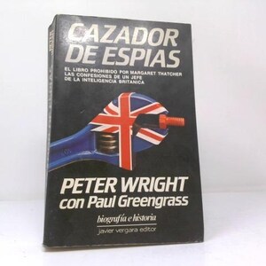 May include: A hardcover book titled Cazador de Espias by Peter Wright with Paul Greengrass. The black cover features a blue adjustable wrench with a Union Jack flag pattern on its head, gripping an orange bolt, with white text throughout the cover.