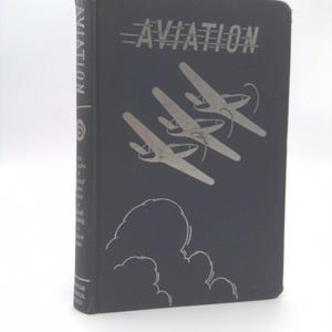 May include: Aviation book with a dark blue cover featuring the title "AVIATION" in silver lettering, along with three silver airplanes and a cloud design. The spine reads "AVIATION" vertically.