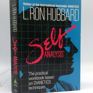 May include: A vintage book titled "Self Analysis" by L. Ron Hubbard. The cover is black with a blue grid pattern and the title in large red letters. The author's name is in white. The book's spine also displays the author's name and title.