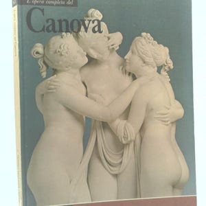 May include: A book titled "L'opera completa del Canova" featuring a sculpture of three figures embracing. The cover has a teal background with the title in large, dark letters. The book is part of the "Classici dell'Arte Rizzoli" series.