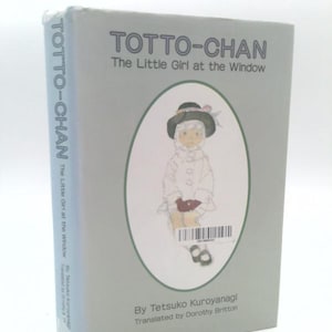 May include: A light gray book titled "Totto-Chan: The Little Girl at the Window." The cover features an illustration of a child in a white coat and hat. The author's name, Tetsuko Kuroyanagi, and translator's name, Dorothy Britton, are also visible.