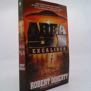 May include: A book cover with a red, orange, and yellow background. The title is "Area 51 Excalibur" in large, silver letters. The author is Robert Doherty, and the book is described as "A Novel." The book cover also features a flying saucer and a sword.