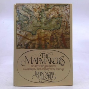 May include: A hardcover book titled "The Mapmakers" with a vintage map illustration on the cover. The book's title is in elegant script, with the author's name below. The cover has a beige background.