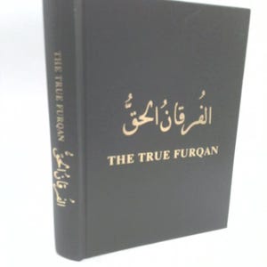 May include: A hardcover book with a black cover and gold lettering. The title "THE TRUE FURQAN" is displayed in English and Arabic script. The book's spine also features the title in gold.