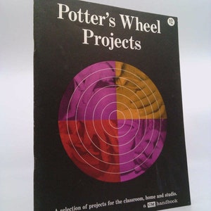 May include: A black and white book cover with the title "Potter's Wheel Projects" and a colorful image of a pottery wheel in the center. The book is a "GM handbook" and includes a selection of projects for the classroom, home, and studio.