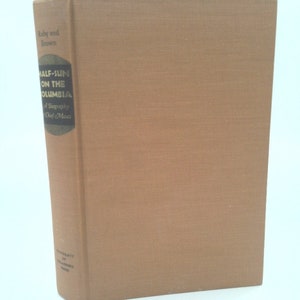 May include: A brown book with the title "Half-Sun on the Columbia" and the text "A Biography of  Chief Moses" on the spine.