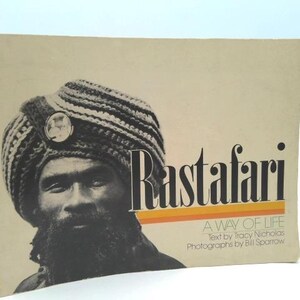 May include: Book cover featuring a black and white portrait of a man wearing a knitted turban with a circular emblem. The title "Rastafari" is displayed in large, stylized letters with an orange and yellow stripe.
