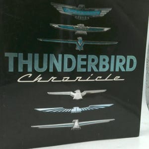 May include: Black book cover with the words "THUNDERBIRD Chronicle" in teal and white. Several silver and teal Thunderbird emblems are displayed above and below the text.