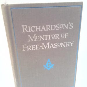 May include: A gray book titled "Richardson's Monitor of Free-Masonry" with blue accents and a Masonic symbol. The book's cover has a blue border and the title is in a serif font. The book is standing upright.