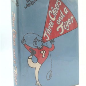 May include: A blue book cover with a red megaphone illustration. The megaphone says "Three Cheers and a Tiger". The book is titled "Three Cheers and a Tiger" and is by Edwin McDowell.