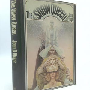 May include: A hardcover book titled "The Snow Queen" by Joan D. Vinge. The cover art features a fantasy illustration with figures in white and gold, with the title in a stylized font. The spine is black.