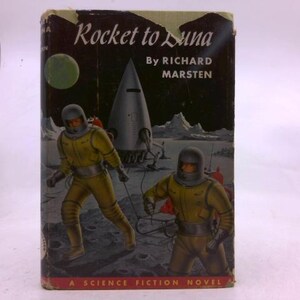 May include: Vintage science fiction book cover titled "Rocket to Luna" by Richard Marsten. The cover art features two astronauts in yellow suits and helmets, a rocket ship, and a green planet against a dark background. The book is labeled "A Science Fiction Novel."