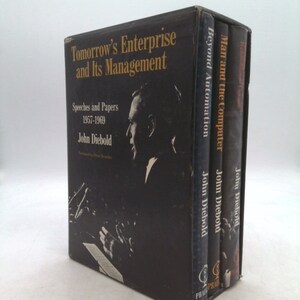 May include: A set of three black hardcover books with gold lettering. The titles are "Tomorrow's Enterprise and Its Management", "Beyond Automation", and "Man and the Computer". All three books are by John Diebold.