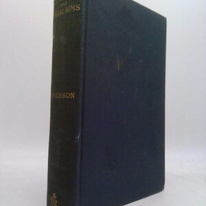 May include: A vintage hardcover book titled "Letters and Social Aims" by Emerson. The book has a dark blue cover with gold lettering. The spine shows wear and tear, suggesting age. The book is standing upright.