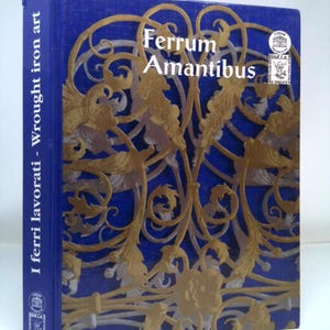 May include: A blue book with the title "Ferrum Amantibus" and the text "I ferri lavorati - Wrought iron art" on the spine. The cover features a gold design of intricate wrought iron work.