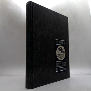 May include: A hardcover book titled "The History of Bannock County 1890-1992." The book has a dark cover with a rectangular label featuring a circular emblem and text. The book is standing upright.