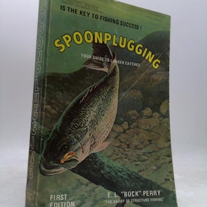 May include: A vintage book titled "Spoonplugging" with a green cover. The cover features a detailed illustration of a fish and the text "Knowledge is the key to fishing success!" The book is a first edition by E.L. "Buck" Perry.
