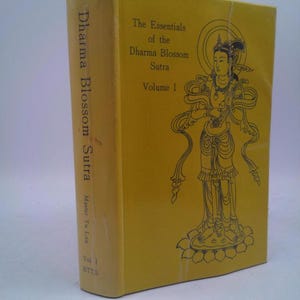 May include: A yellow book titled "The Essentials of the Dharma Blossom Sutra, Volume I" by Master Tu Lun. The cover features a line drawing of a figure. The spine reads "Dharma Blossom Sutra".