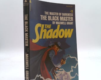 May include: A paperback book cover with a blue background featuring a man in a black suit and cape holding a glowing orb. The text on the cover reads "The Master of Darkness #2 The Black Master by Maxwell Grant The Shadow".
