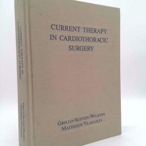 May include: A hardcover book titled "CURRENT THERAPY IN CARDIOTHORACIC SURGERY." The book has a light tan cover with the title in dark blue. The author's names are printed at the bottom of the cover.